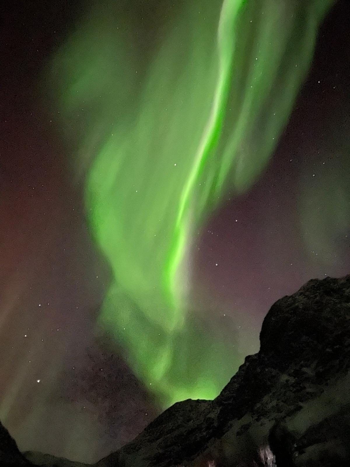 Northern lights above a dark mountain ridge