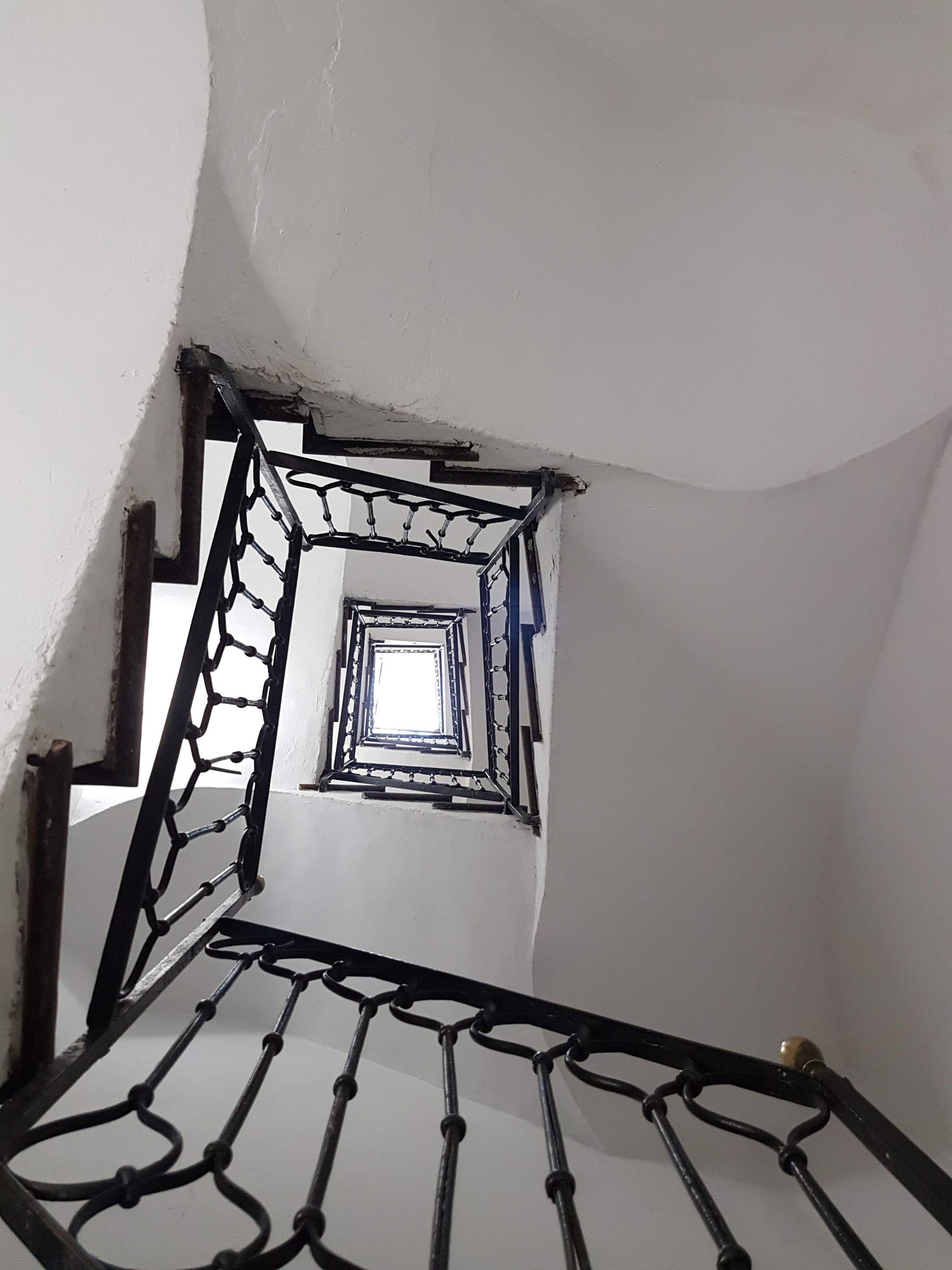 A spiral stairwell seen from above, receding toward light